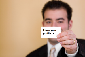 Man in suit holding a business card saying I love your profile.