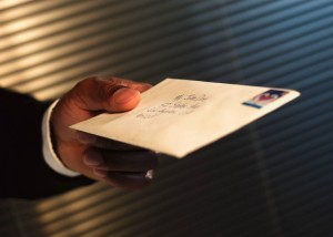 Man hading a letter to someone with a heart shaped stamp.